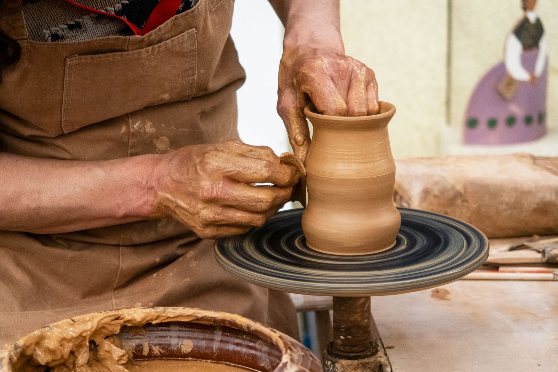 A potter’s hands shaping clay on a pottery wheel